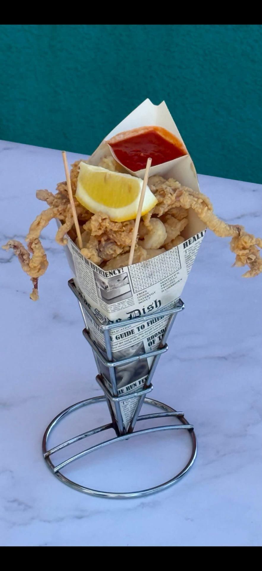 Golden fried calamari served in a newspaper cone with lemon and marinara